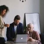 Discussion Clock - Diverse coworkers using laptop and speaking about job