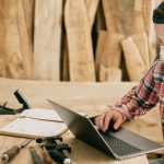 Laptop Tools - Man Using a Laptop at a Wood Workshop