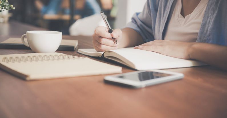 Internship Application - Woman Writing on a Notebook Beside Teacup and Tablet Computer