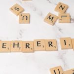 Mentorship - Scrabble tiles spelling lehrerin on a white marble surface
