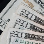 Money Growth - Stack of dollars and black envelope with banknotes inside