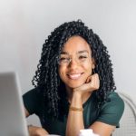 Happy Student - Happy ethnic woman sitting at table with laptop