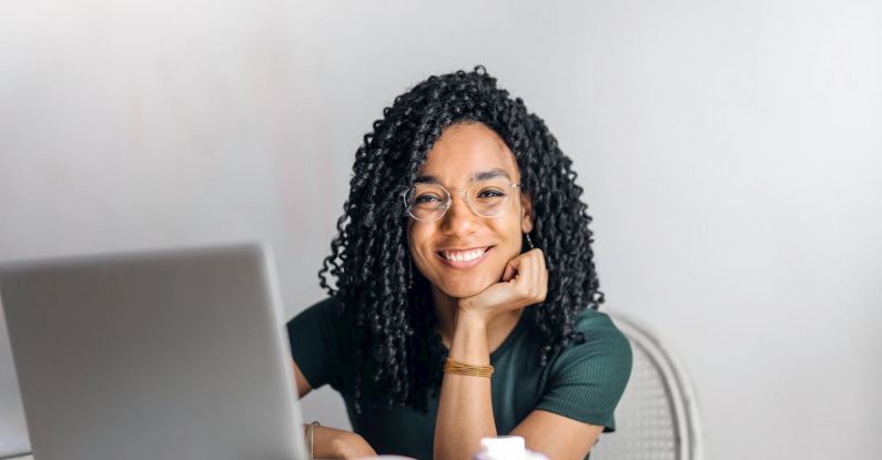 Happy Student - Happy ethnic woman sitting at table with laptop