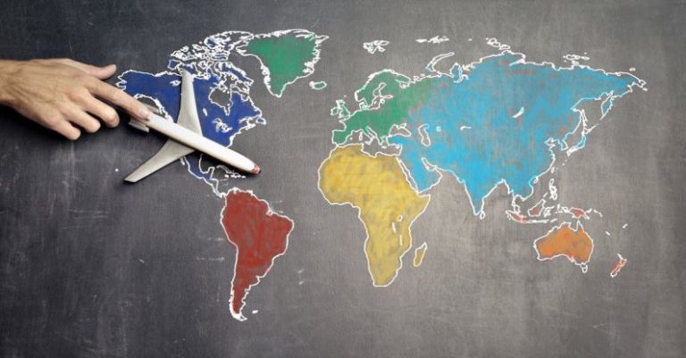 Strategy Plan - Top view of crop anonymous person holding toy airplane on colorful world map drawn on chalkboard