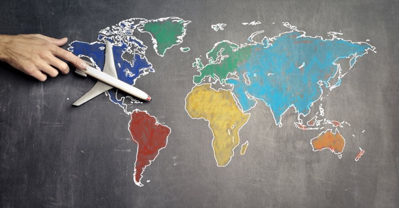 Strategy Plan - Top view of crop anonymous person holding toy airplane on colorful world map drawn on chalkboard